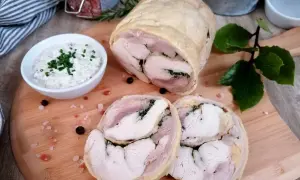 Pyszna galantyna z kurczaka, pokrojona w plastry, podana z kremowym sosem. Idealna na elegancki obiad.