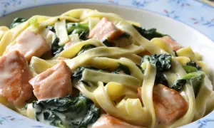 Pyszne tagliatelle z kawałkami łososia i świeżym szpinakiem w kremowym sosie. Idealne danie dla miłośników makaronu z łososiem i szpinakiem.