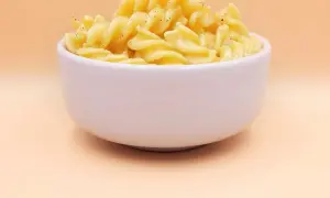 Pyszny makaron z jajkiem i pieprzem w białej miseczce, gotowy do zjedzenia.
