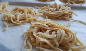 Świeży, domowy makaron do rosołu, uformowany w apetyczne gniazdka, czeka na gotowanie.