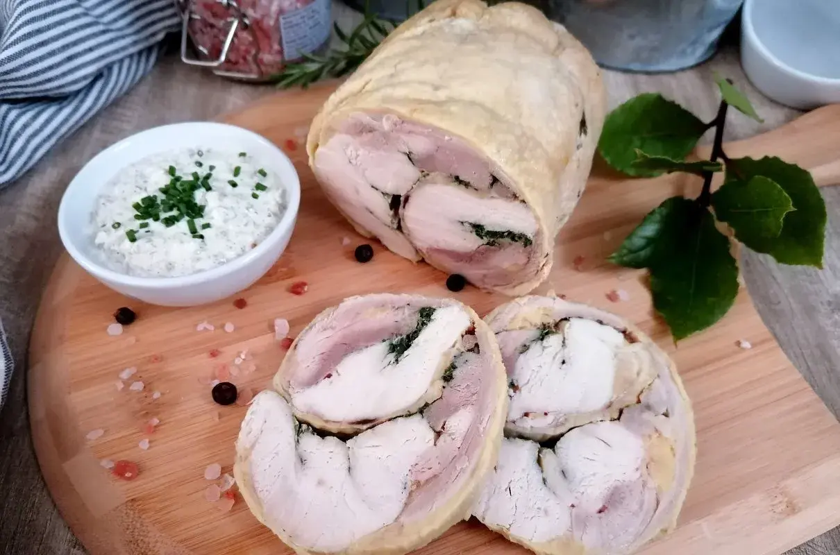 Pyszna galantyna z kurczaka, pokrojona w plastry, podana z kremowym sosem. Idealna na elegancki obiad.