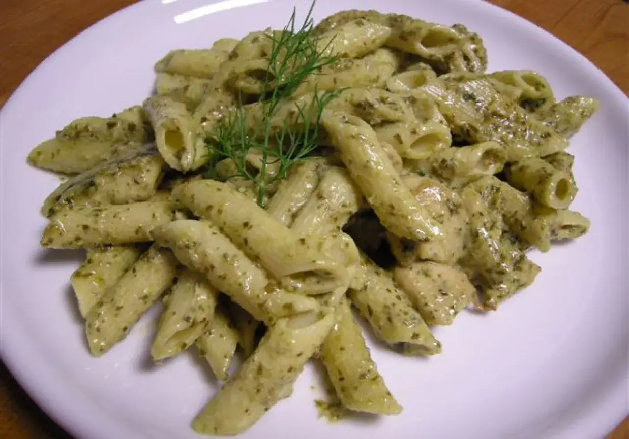 Penne z kurczakiem w sosie pesto, udekorowane gałązką koperku. Pyszne danie na obiad.