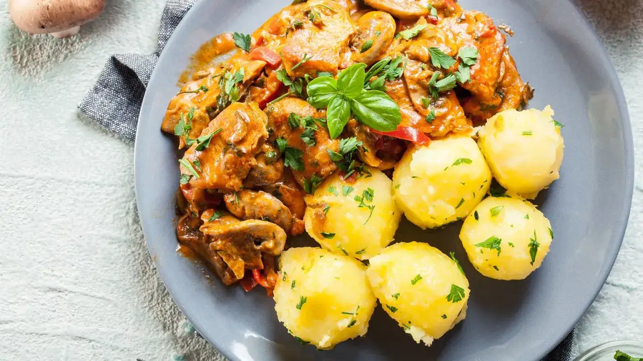 Pyszny gulasz z indyka w sosie z pieczarkami i papryką, podany z kluskami ziemniaczanymi.