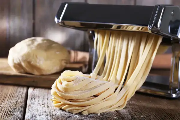 Domowy makaron jak u babci, świeżo wyciskany przez maszynkę. Ciasto czeka na swoją kolej.