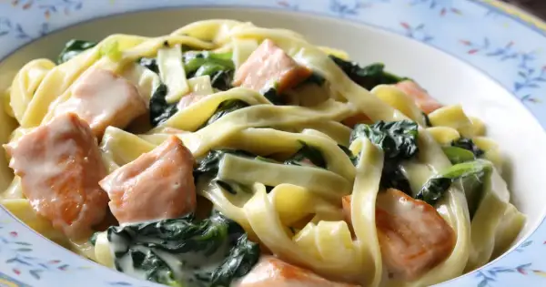Pyszne tagliatelle z kawałkami łososia i świeżym szpinakiem w kremowym sosie. Idealne danie dla miłośników makaronu z łososiem i szpinakiem.